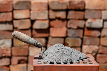 Dry cement or mortar. Cement powder and trowel on red brick at construction site, closeup