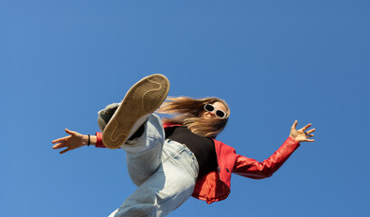 Dynamic low angle shot of a young woman boldly stepping forward against a clear blue sky. vitality, freedom and joy, motivation to move. copy space.