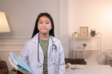 An Asian girl wearing a medical gown with a stethoscope looks at the camera.