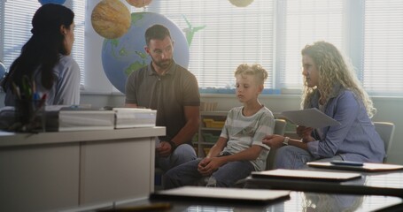 Parents Looking at School Exam Grades of Their Son in Classroom. Teacher and Parents Discussing...