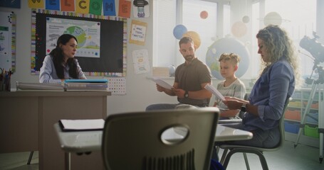 Female Teacher Giving School Exam Results of Young Boy to His Parents. Teacher and Parents...
