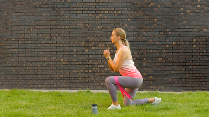 Woman exercising outdoors with resistance band and water bottle