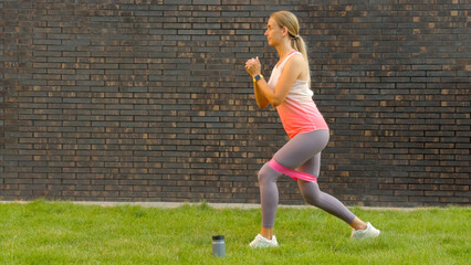 Woman exercising outdoors with resistance band and water bottle