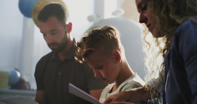 Teacher Giving School Exam Results of Young Boy to Parents in Classroom. Parents Upset About Academic Failure of Primary School Student. Meeting to Support Child's Development. Slow Motion. Close Up.