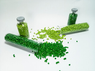 Green polymer masterbatch gradation, green pigment resin pellets in glass tubes poured on a white...