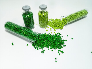 Green polymer masterbatch gradation, green pigment resin pellets in glass tubes poured on a white...