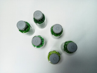 Green polymer masterbatch gradation, green pigment resin pellets in glass tubes poured on a white...