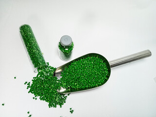 Green polymer masterbatch gradation, green pigment resin pellets in glass tubes poured on a white...