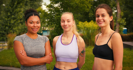 Women athletes in sportswear stand together in city park