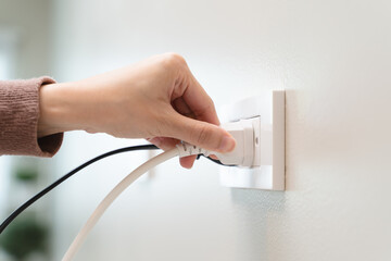 Close-up hands pull off electronic device plug after finish used.