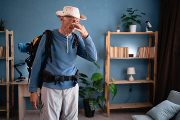 Bad smell stinks. Elderly traveler with backpack pinching nose with disgust at home. Tourist likes...