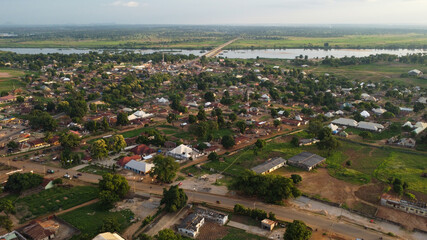 Expansive aerial view showcasing a vibrant African town nestled along a river and a bridge.