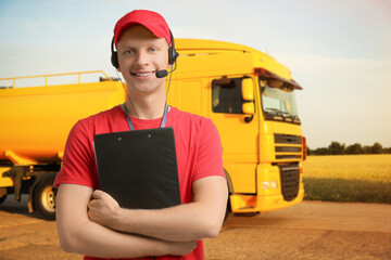 Car service worker with headset and clipboard against truck outdoors. Client support