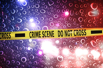 Police yellow Crime Scene Do Not Cross tape. Red and blue lights, blurred view through wet glass