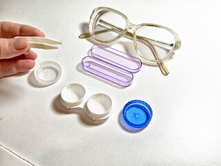 Tools for contact lens care and eyewear maintenance on a white surface during daylight