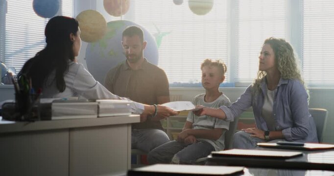 Mother and Father Looking at School Test Grades of Their Son During Parents Evening. Teacher and Parents Happy About Excellent Academic Performance and Behavior of Elementary School Boy. Medium Shot.