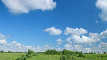 Tranquil and Beautiful Green Hills Under a Bright Blue Sky with Fluffy White Clouds
