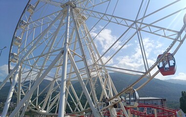 Ferris wheel with a joyous mood, representing summer amusement against mountains and blue sky