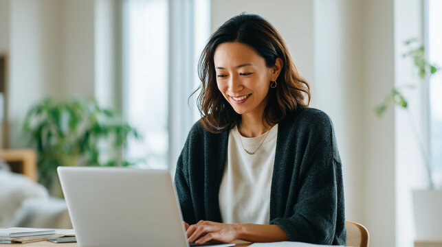 Asian Woman Working Remotely with Laptop in Bright Modern Office