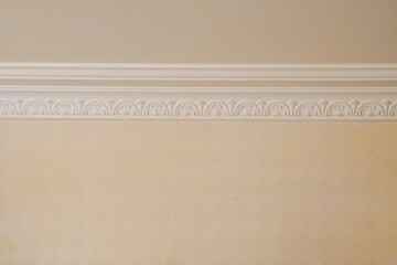 Elegant white crown molding with an ornate classical pattern against a beige painted wall. © Tho in your picture