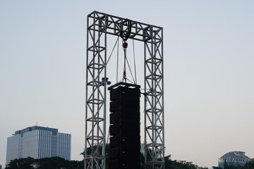 Professional line array speakers suspended from a metal truss for an outdoor event.