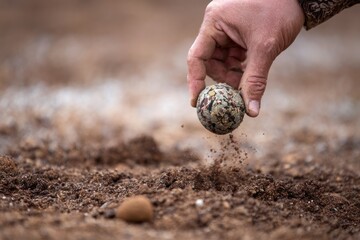 Hand releasing a patterned ball into dusty ground