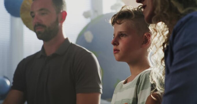 Mother and Father Looking at School Test Results of Their Son During Parents Evening. Parents Happy About Excellent Academic Performance and Behavior of Elementary School Boy. Slow Motion. Close Up.