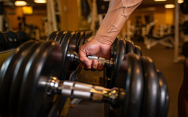 Close up of a hand gripping a heavy dumbbell in a gym