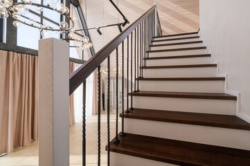 Elegant staircase with dark wood steps and white risers, complemented by a black iron railing in a...