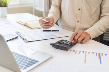 Stressed asian young businessman, employee male using calculator to calculate expenses of monthly,...