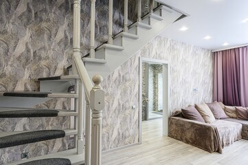 cozy interior featuring a light-colored staircase with gray carpet treads, textured wallpaper, a...