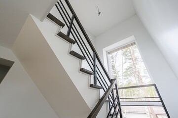 modern staircase with dark wood steps and black metal railings in a bright, white interior space. A...