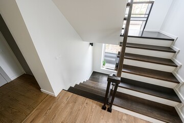 modern staircase with dark wood steps and white risers. Natural light streams in, highlighting the...