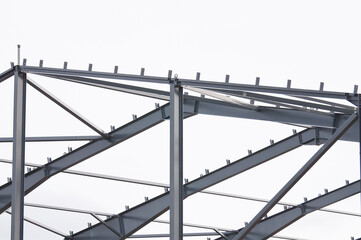 Metal construction, in the photo the structure of the building frame made of metal beams against the background of a gray sky