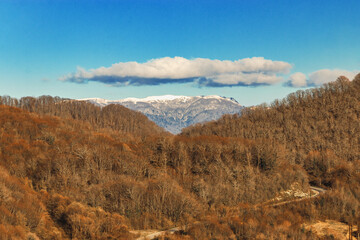 A colorful landscape with high mountains, a beautiful winding river, an autumn forest, and a blue sky with clouds. Stunning view of the river among the colorful autumn forests. Autumn in the mountains