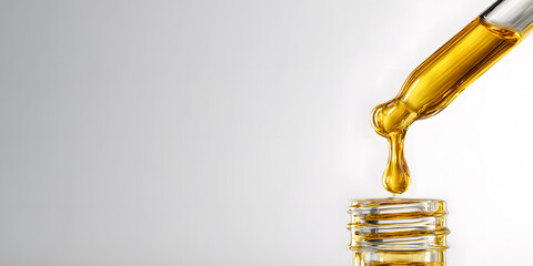 A dropper releases a golden liquid into a small glass container, showcasing the essence of high-quality oil extraction