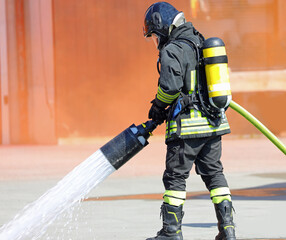 firefighters with oxygen tanks and protective helmets spraying white foam during an emergency