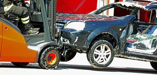 orange forklift for handling damaged car after road accident in scrapyard