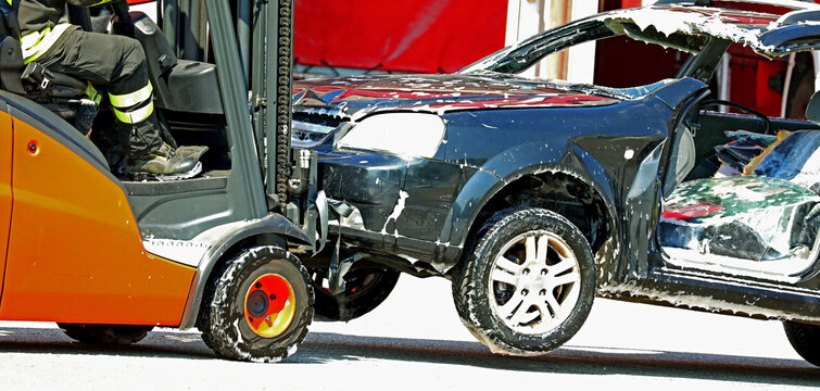 orange forklift for handling damaged car after road accident in scrapyard