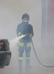 firefighter with uniform and helmet spraying extinguishing agent and foam into car that caught fire...