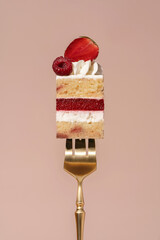 Vanilla sponge bento cake layered with raspberry and strawberry, topped with whipped cream and fresh fruit, presented on a golden fork against a soft pastel background, dessert concept