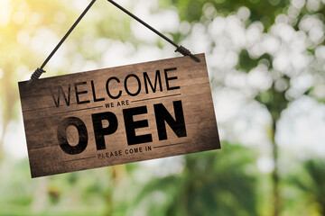 Store owner turning open sign broad through the door glass and ready to service.