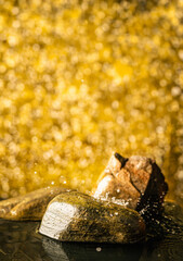 Gold background with fashion natural stone podium with water and splashes for packaging and cosmetic presentation, place for the product