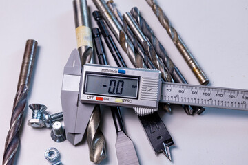 Various metal tools and hardware displayed with a digital caliper on a workbench in a workshop, showcasing precision measurement and craftsmanship