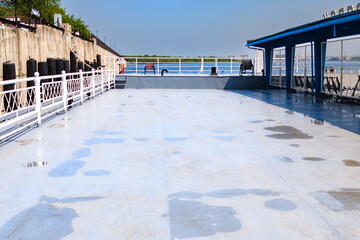 Deck of a riverboat docked at the waterfront, showcasing blue skies and clean surfaces, perfect for gatherings on a sunny afternoon by the water