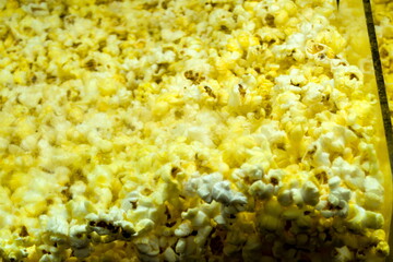 Freshly popped popcorn fills a large container at a busy movie theater during the evening screening of a popular film
