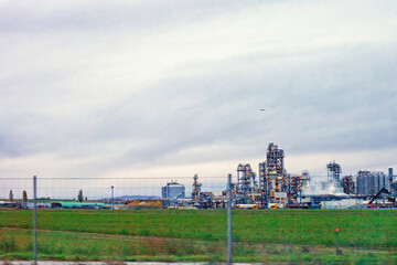 Crude oil refinery plant and green meadow. Summer lush fields and factory complex