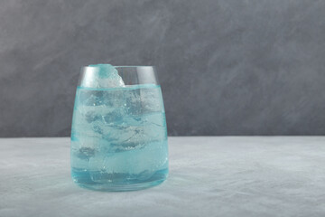 Glass of Blue refreshing drink with ice cubes. Light blue lemonade. Iced summer cocktail