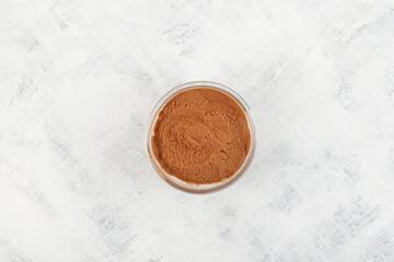 Natural Guarana seed powder in glass bowl on the table, top view. Cupana tea extract. Guarana seeds are naturally rich in caffeine