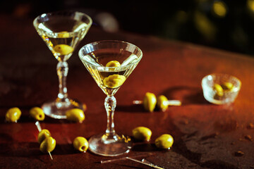 A pair of martinis in crystal glasses, set in an upscale lounge with warm ambient lighting.